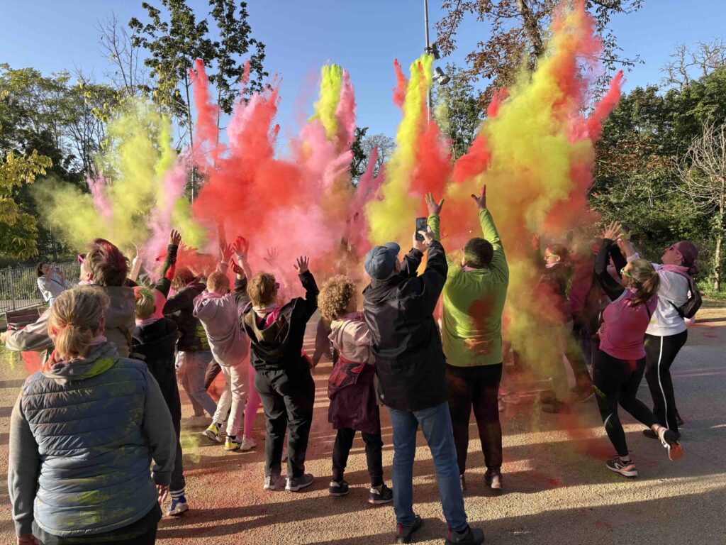 Une foule de personne lance la poudre de plusieurs couleurs lors d'un Team Building