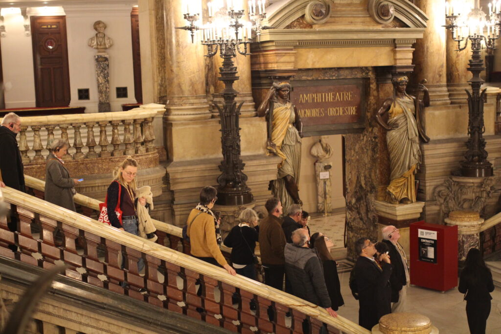 Un groupe dans le grand hall d'entrée de l'Opéra Garnier Paris descend les marches.