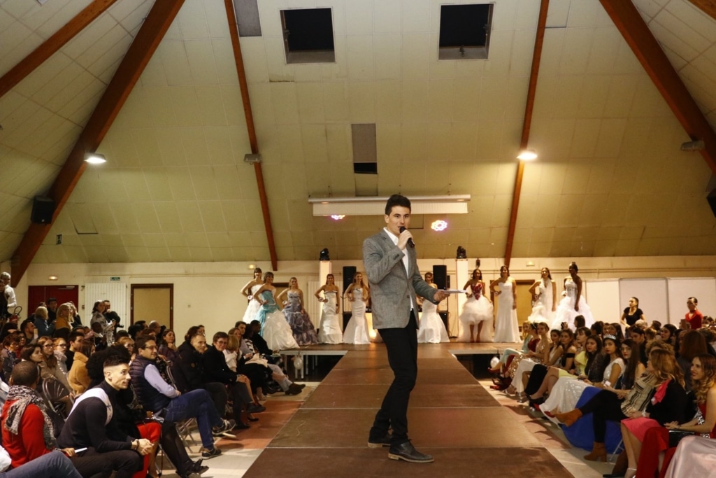 un maître de cérémonie sur une scène, entouré du public.