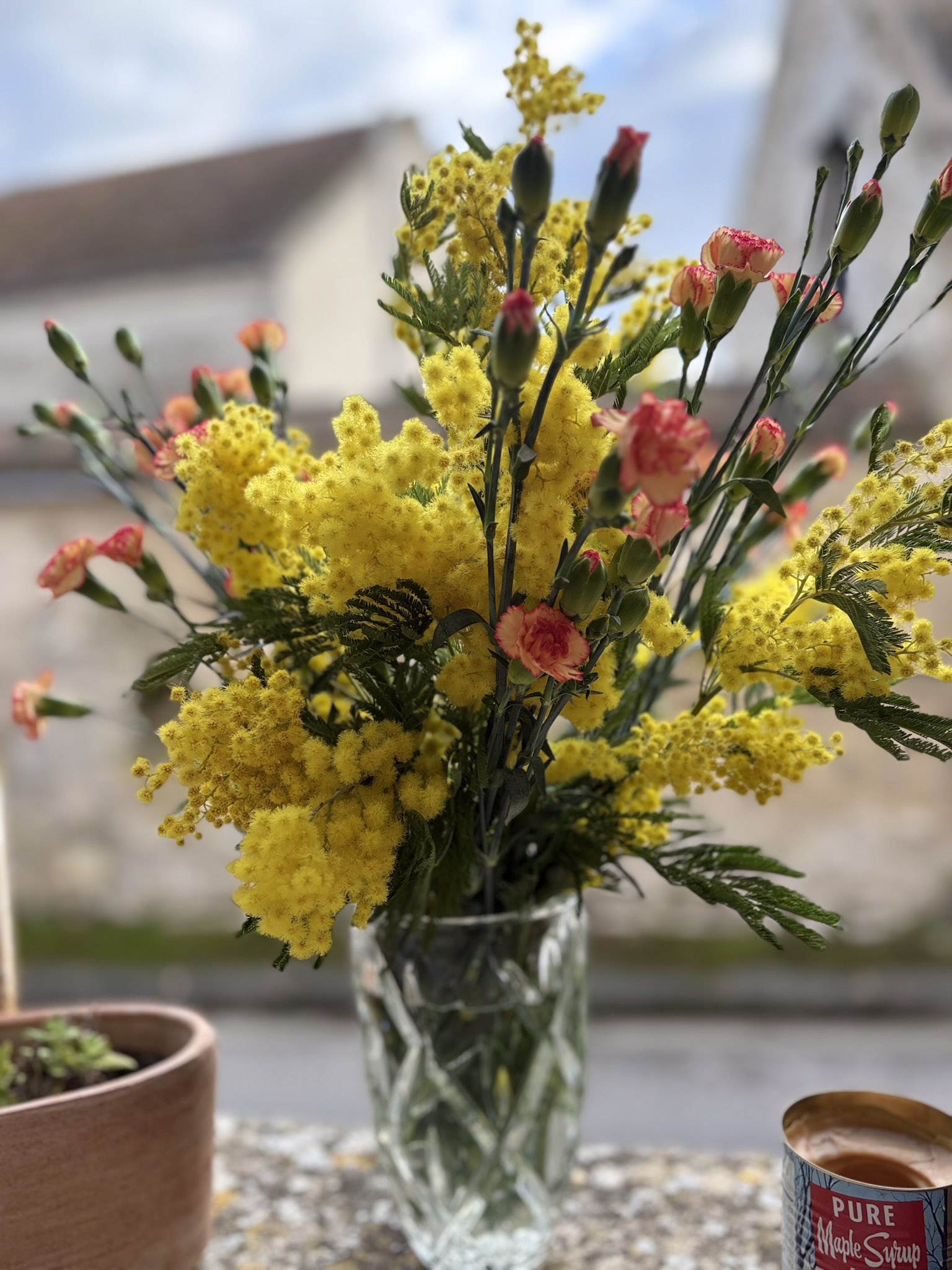 un bouquet de fleurs au balcon d'un village en pierre avec des mimosas