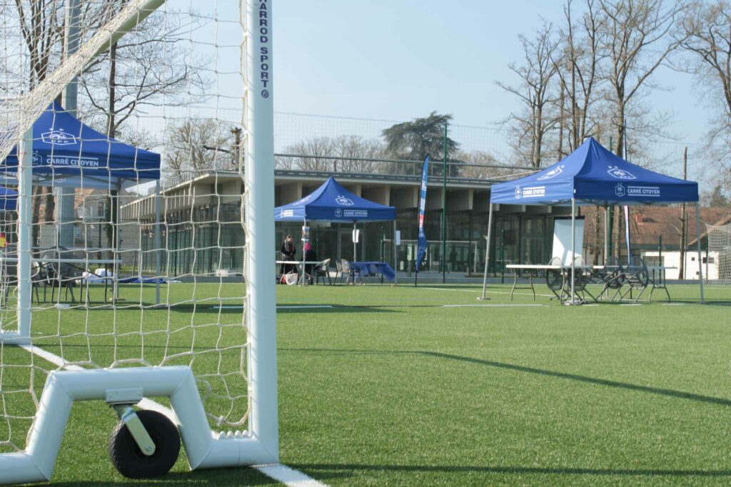 un terrain de football synthétique avec des tentes type stand