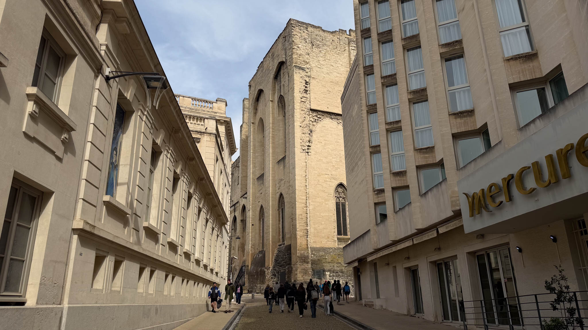 Une ruelle du centre-ville d'Avignon avec quelques piétons par ciel bleu