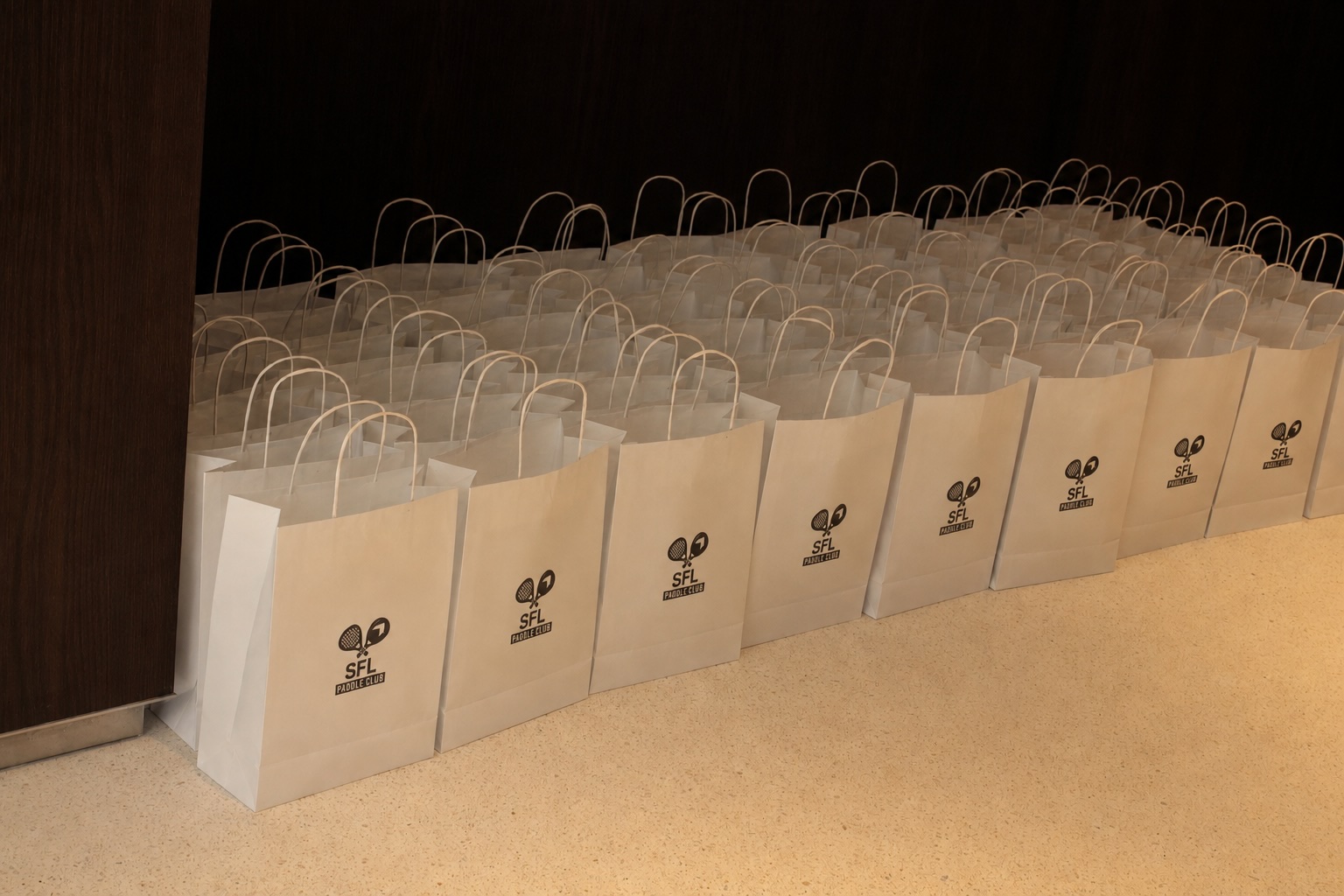 des sacs de cadeaux blancs avec un logo rangés les uns à côté des autres lors d'un événement