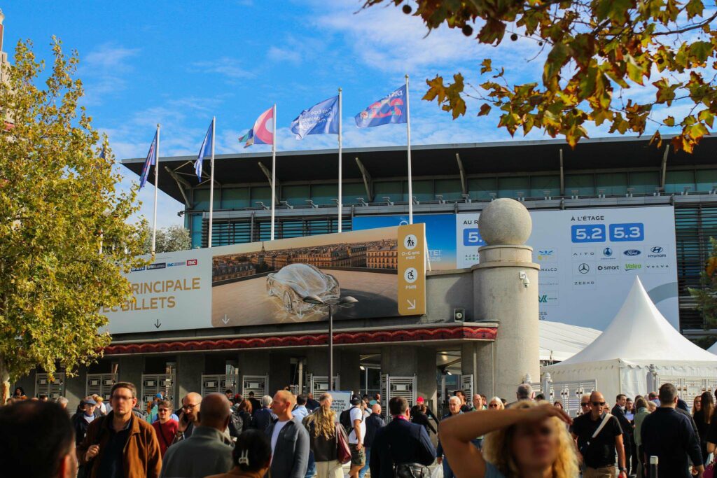 the entrance of a professional trade show in Paris with an entrance arch and a pavilion in the background with flags.