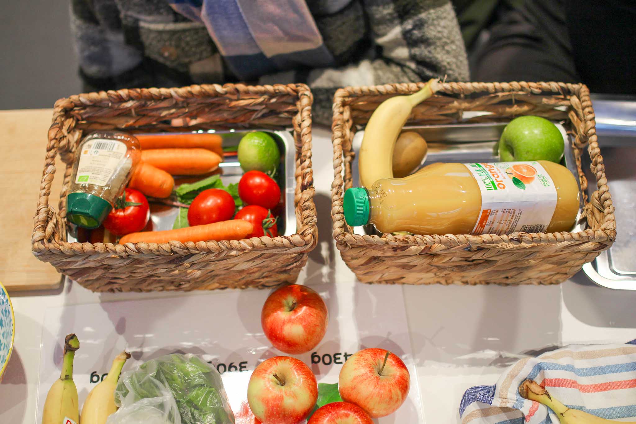 deux paniers de marché en osier remplis de fruits et légumes.